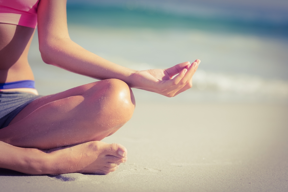 Close up view of fit woman doing yoga beside the sea  at the beach